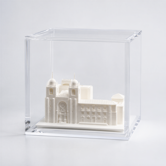 A small white model of a building, possibly a church or cathedral, displayed in a clear glass case.