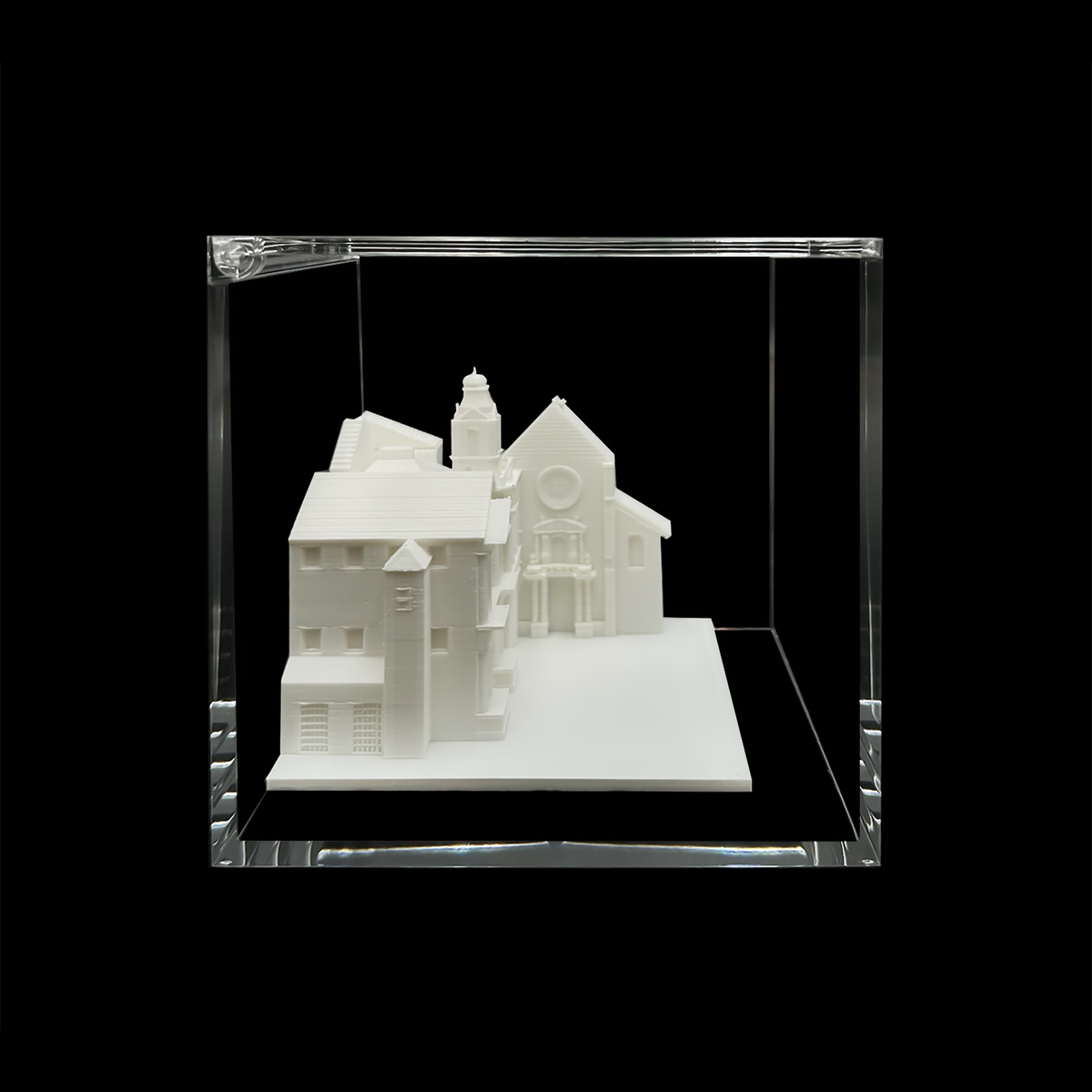 A 3D model of a building displayed in a clear glass case against a black background.