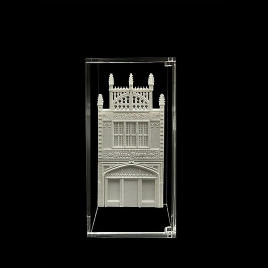 A white, ornate, and intricately designed building is displayed in a clear glass case against a black background.