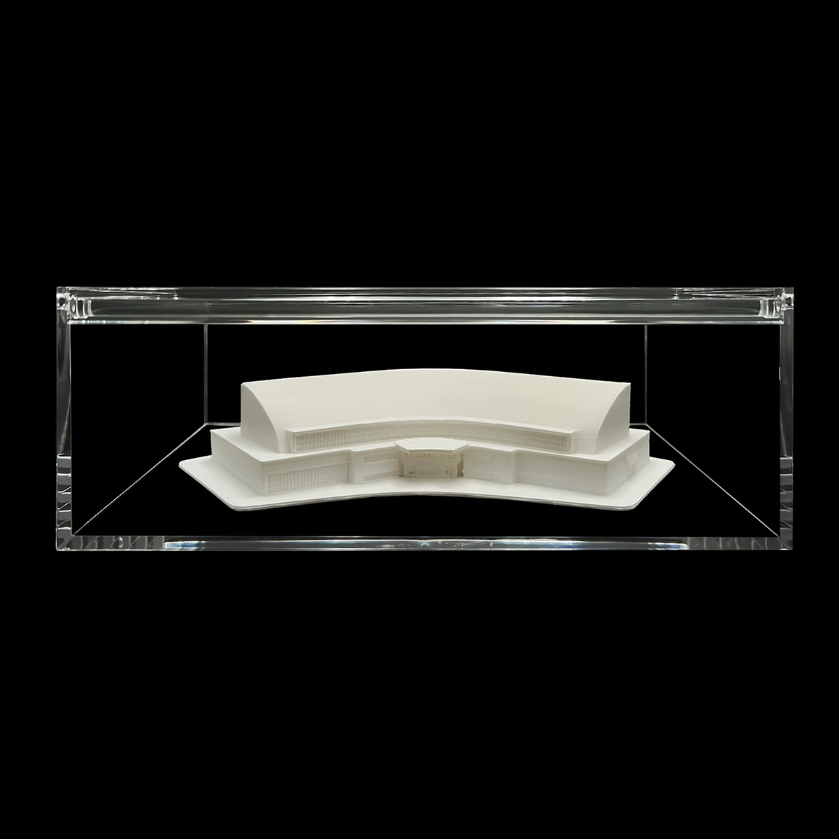 A white, three-dimensional model of a building or structure displayed in a clear, transparent case against a black background.