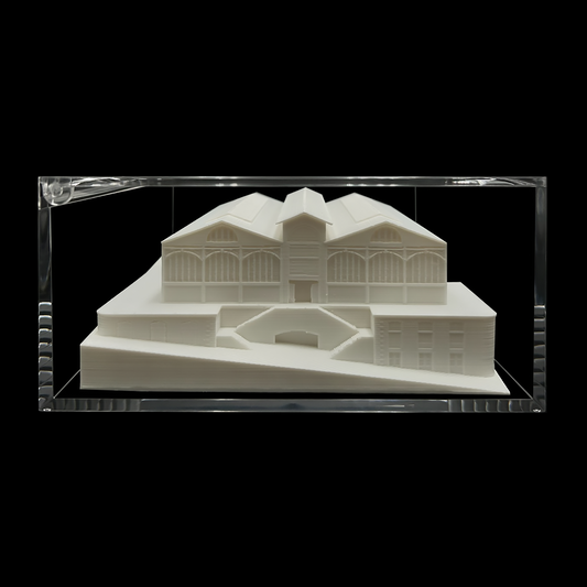 A white 3D model of a building displayed in a clear glass case against a black background.
