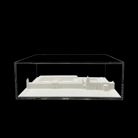 A 3D model of a building displayed in a clear glass case against a black background.