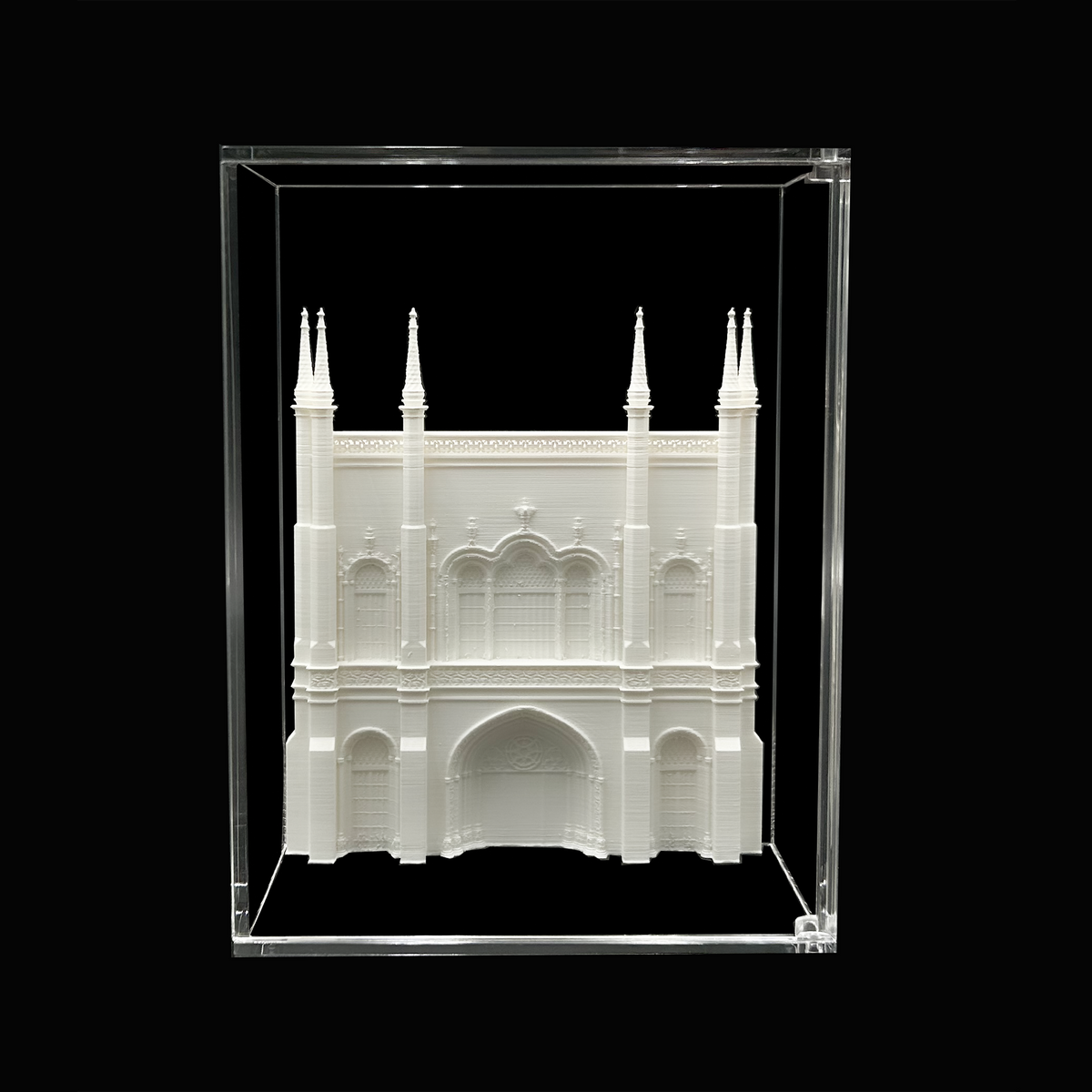 A 3D model of a white architectural structure, possibly a cathedral or palace, displayed in a clear glass case against a black background.