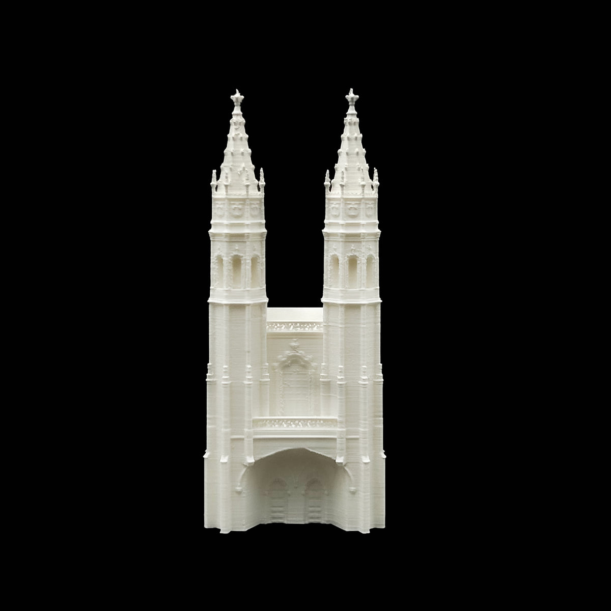 A white, three-dimensional model of a church with two tall spires and a central archway.