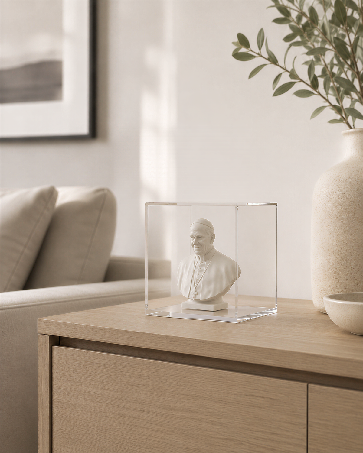 a small bust of a person displayed in a clear glass case on a wooden table.
