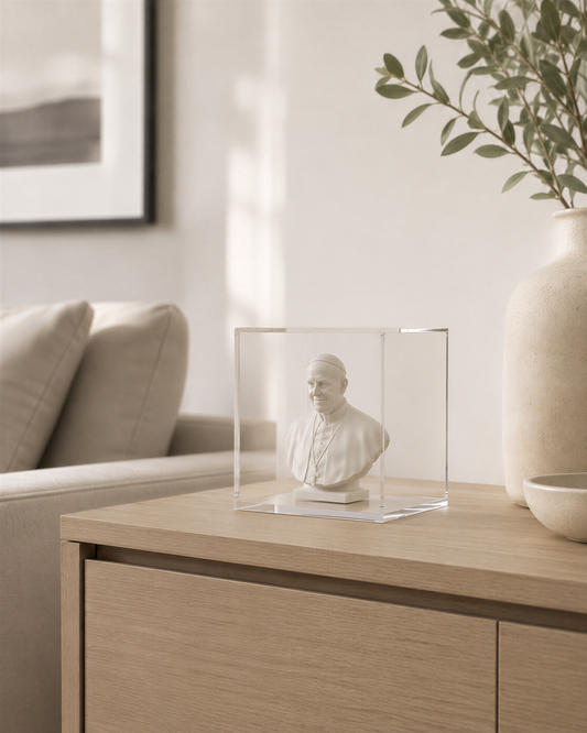 a small bust of a person displayed in a clear glass case on a wooden table.