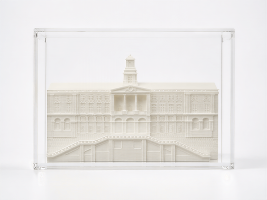 A white, three-dimensional model of a building with a tower, displayed in a clear glass case.