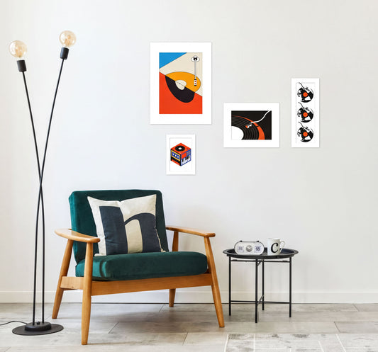 a modern living room with a green armchair, a black side table, and a floor lamp. The wall is decorated with four framed abstract artworks, including a large orange and black abstract piece, a smaller black and white abstract piece, and two smaller black and white abstract pieces.
