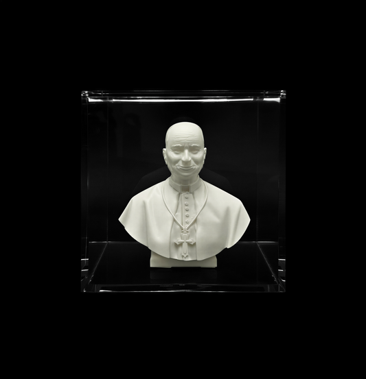 A white bust of a man wearing a religious collar, displayed in a clear glass case against a black background.