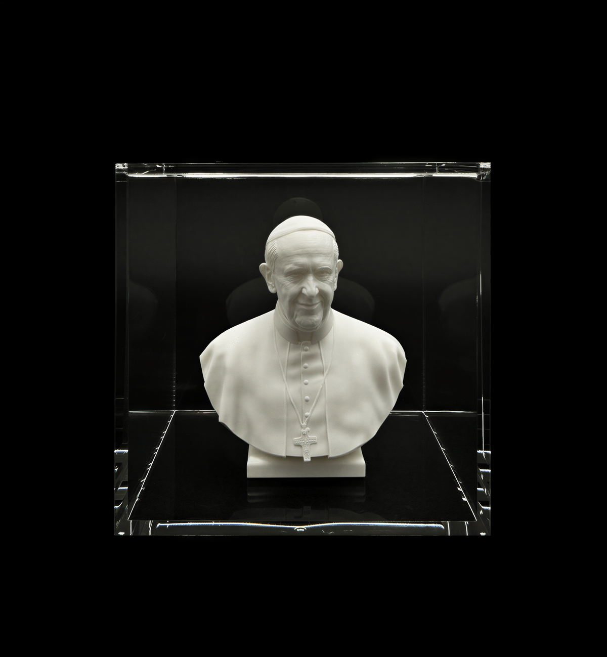 A white bust of a man wearing a religious collar, likely representing a religious leader, displayed in a glass case.