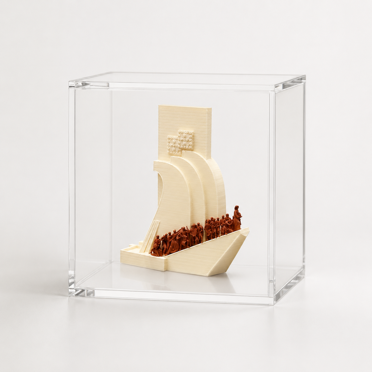 A small, white, three-dimensional sculpture of a ship or boat is displayed in a clear glass case.