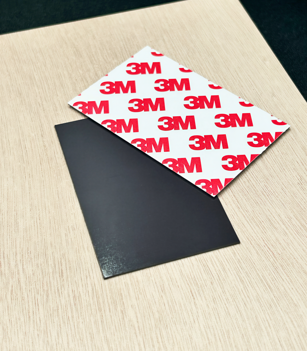 a black object placed on a wooden surface, with a white object with red text on it lying on top of it.