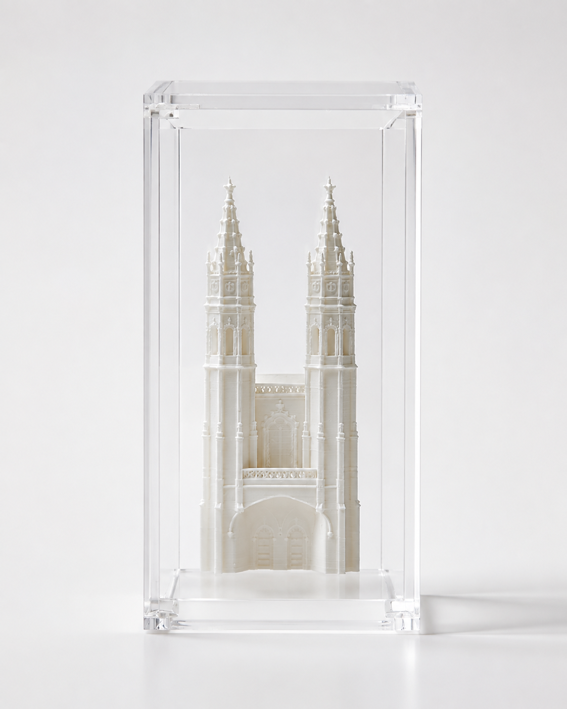 A miniature white model of a cathedral or church, displayed in a clear glass case.
