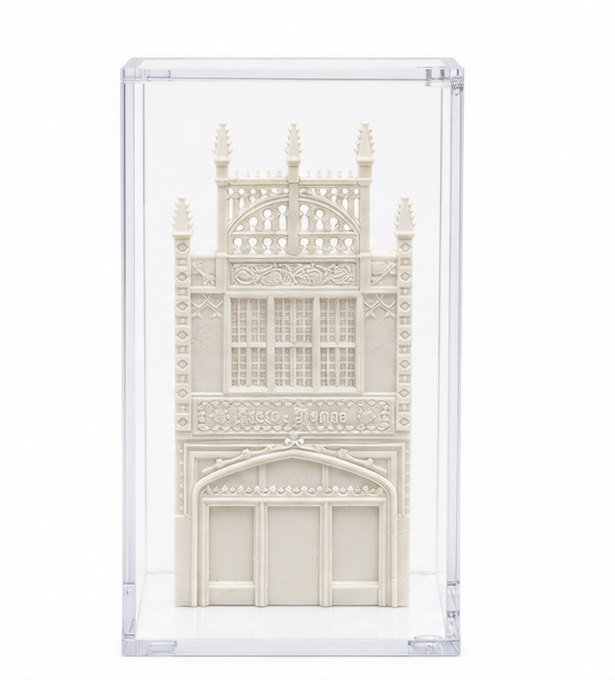 A white, ornate, and intricately designed miniature model of a building, displayed in a clear glass case.