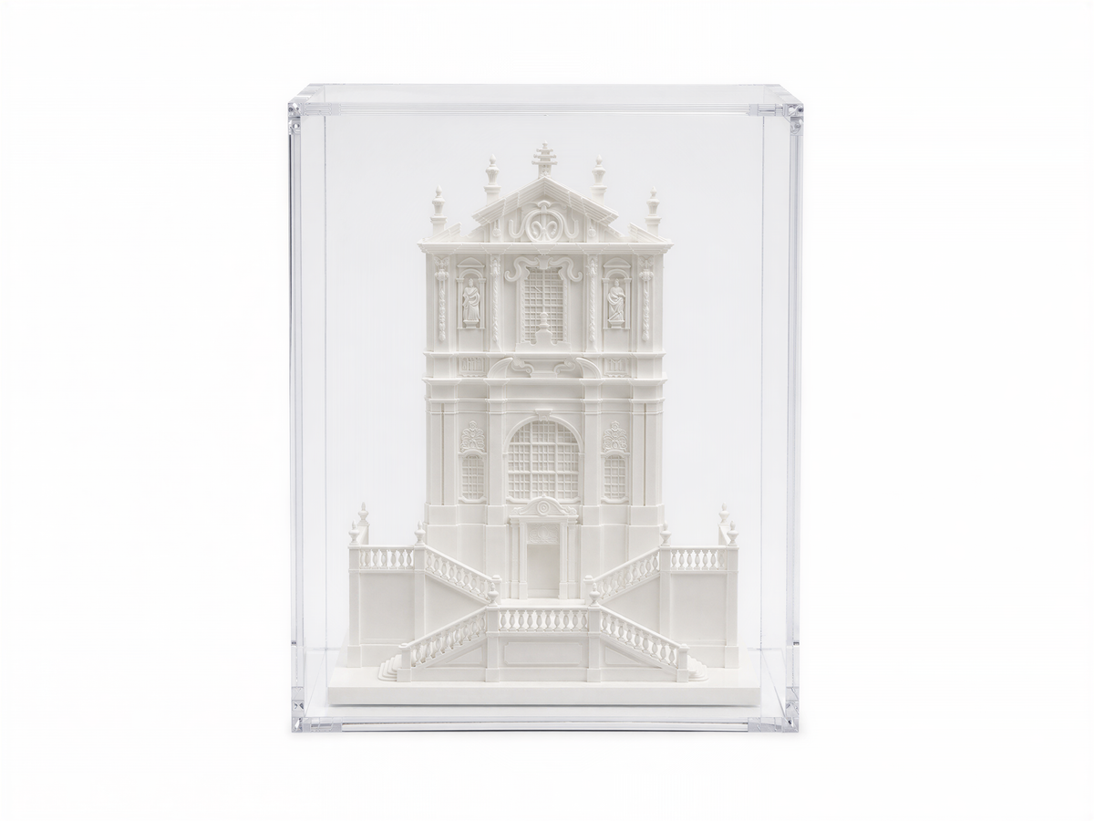 A white, ornate, and intricately designed building is displayed in a clear glass case.