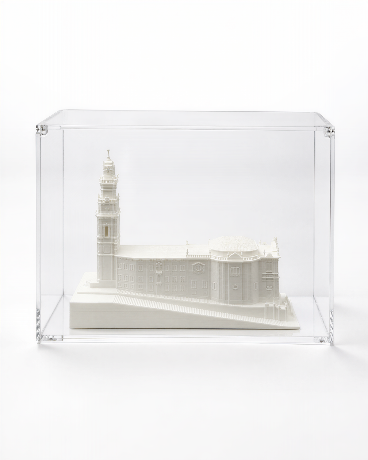 A white ceramic model of a building, possibly a church or cathedral, displayed in a clear glass case.