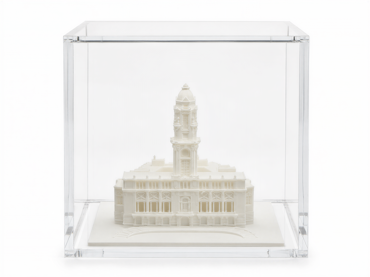 A white miniature model of a building, possibly a tower, displayed in a clear glass case.