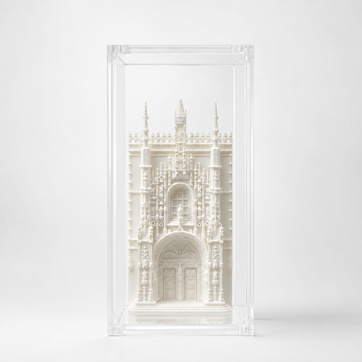 A white, intricate, and ornate miniature model of a building, possibly a church or cathedral, displayed in a clear, transparent frame.
