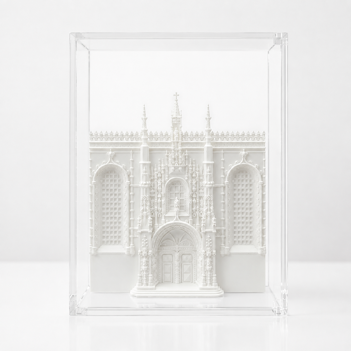 A white, three-dimensional model of a building, possibly a church or cathedral, displayed in a clear, transparent case.