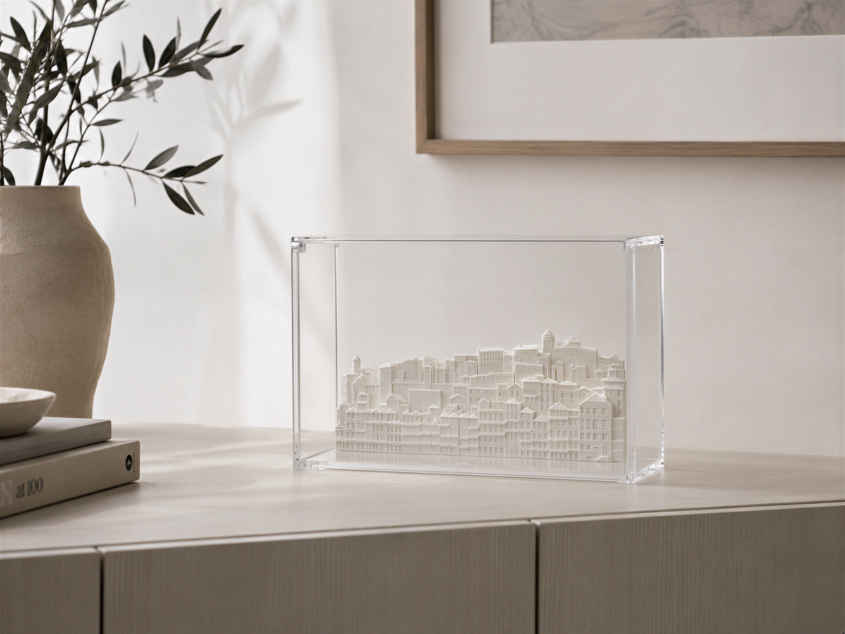 a clear glass box containing a miniature model of a cityscape, placed on a wooden surface.