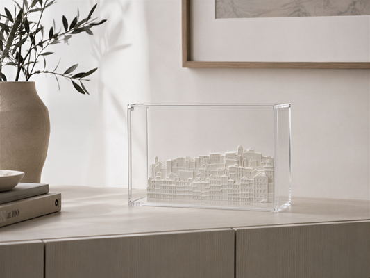 a clear glass box containing a miniature model of a cityscape, placed on a wooden surface.