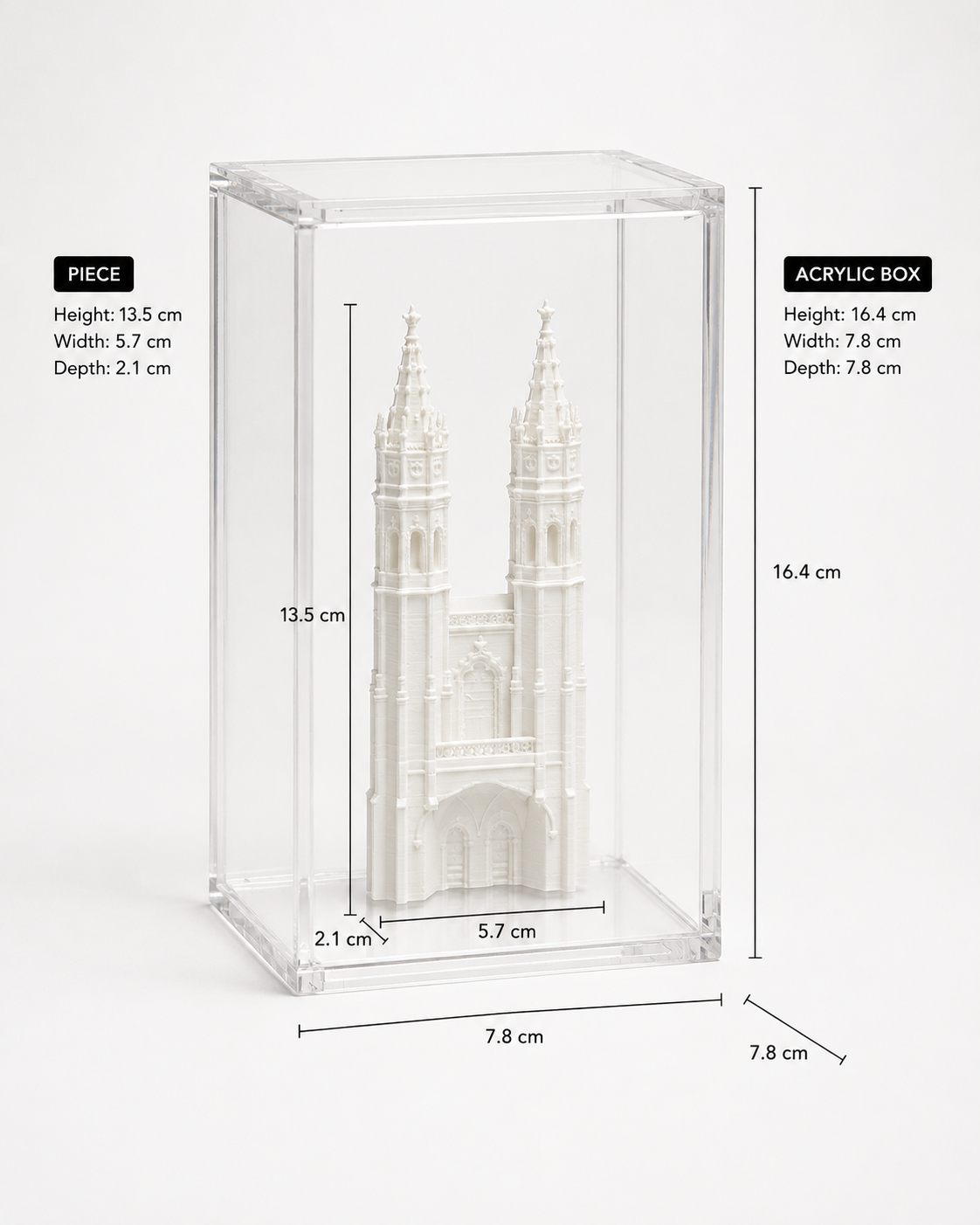 a small white model of a cathedral or church, displayed in a clear plastic case. The case has a height of 13.5 cm, a width of 5.7 cm, and a depth of 2.1 cm.