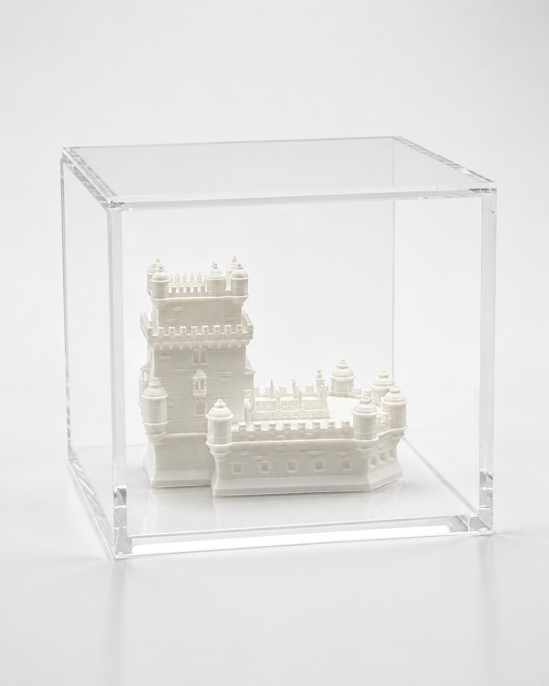 A small white model of a castle or palace is displayed inside a clear glass case.