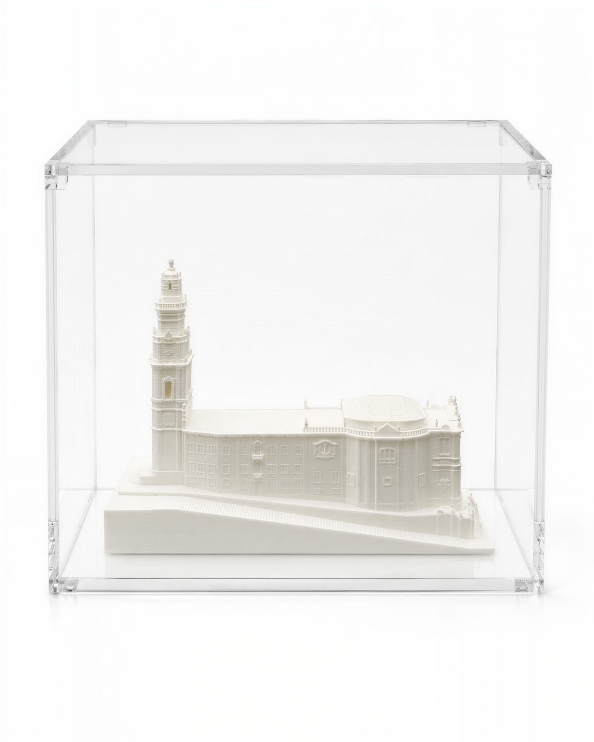 A white miniature model of a building, possibly a church or cathedral, displayed in a clear glass case.