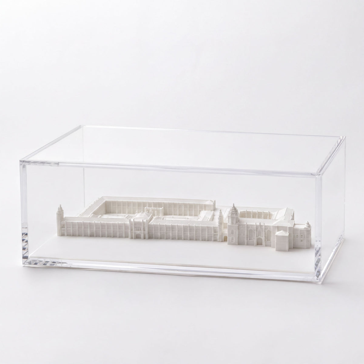 A white model of a building displayed in a clear glass case.