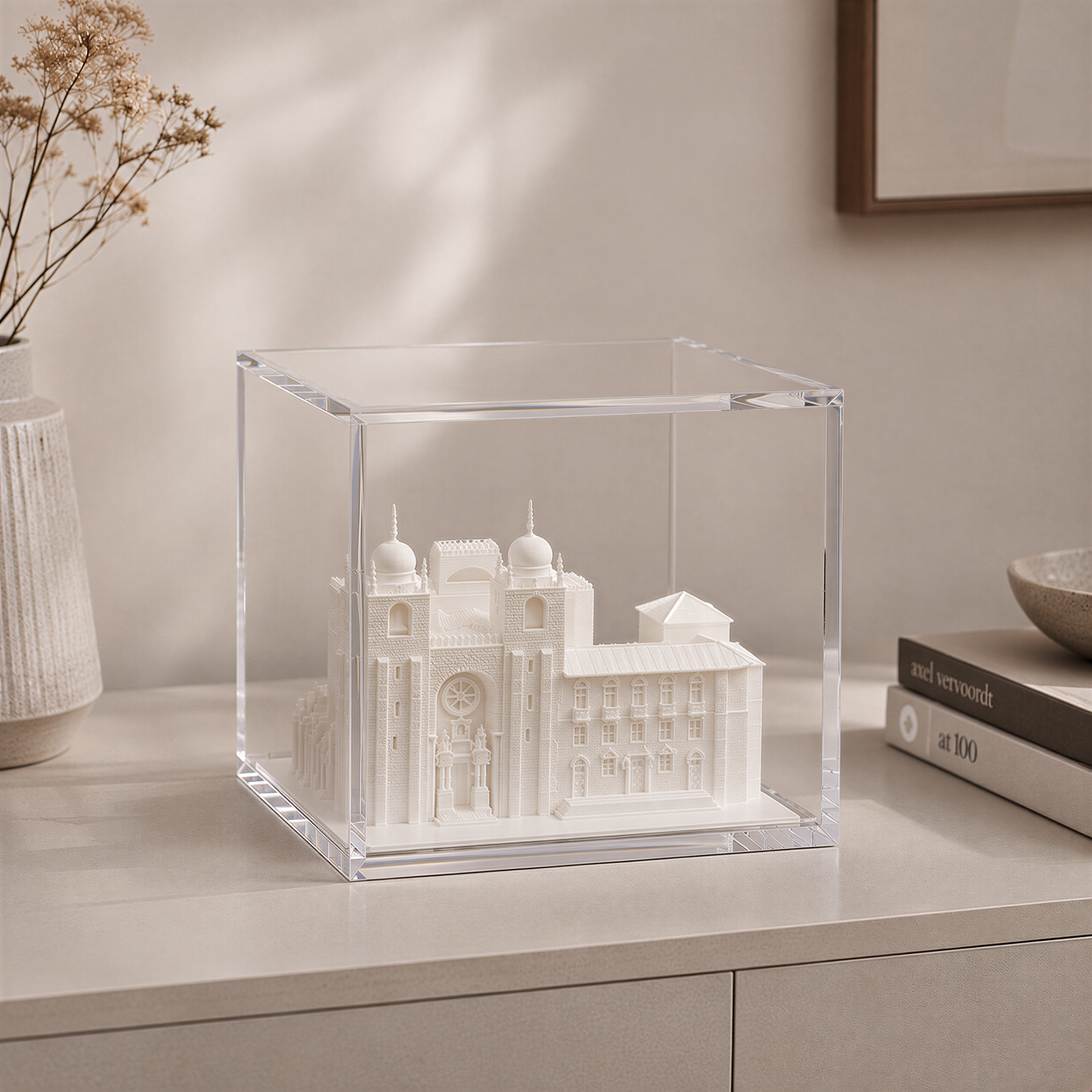 A clear glass display case containing a miniature model of a building, likely a historical or architectural landmark, on a table.
