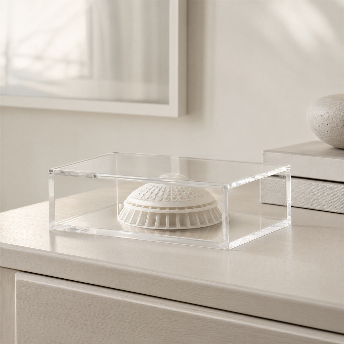 A clear glass display case containing a white ceramic object, possibly a decorative piece or a figurine, sits on a wooden surface.