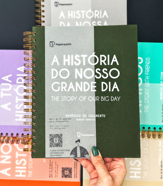 a person holding a book titled "A HISTORIA DO NOSSO GRANDE DIA" (The History of Nossa), which is a book about the history of Nossa. The book cover has a green and white color scheme, and the text on the cover is in Portuguese.