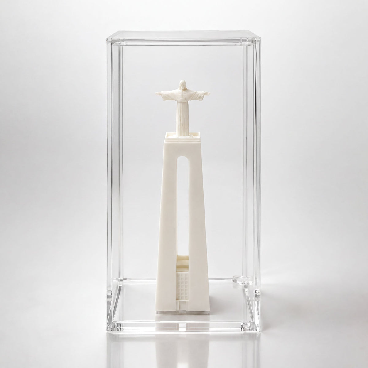 A small white statue of Christ inside a clear glass case.