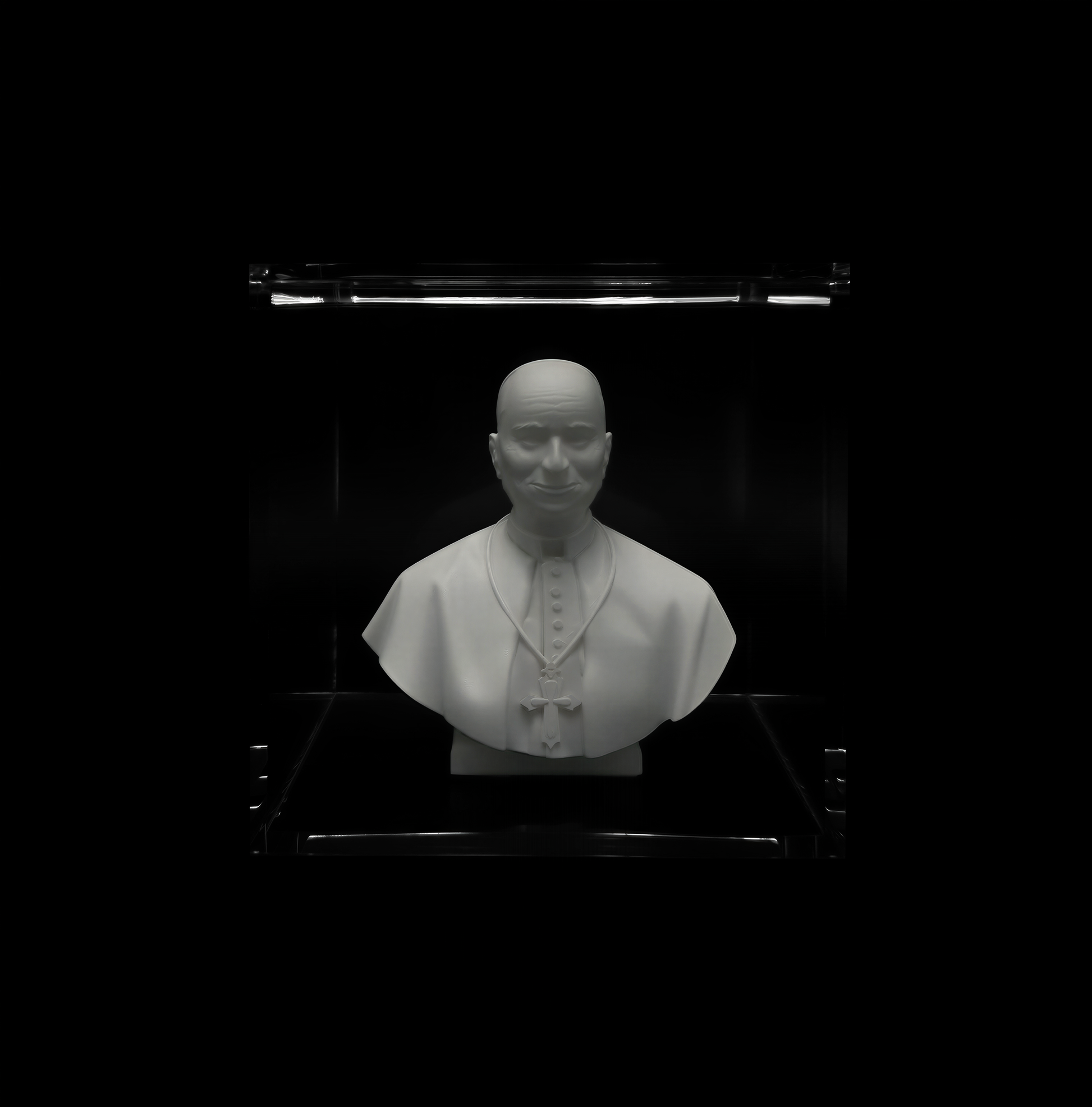 A white bust of a man wearing a white robe and a white hat, displayed in a glass case against a black background.