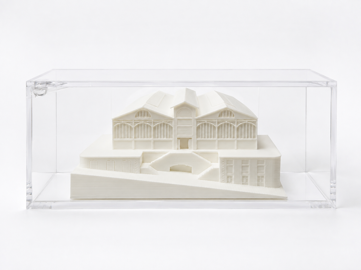 A 3D model of a building displayed in a clear plastic case.