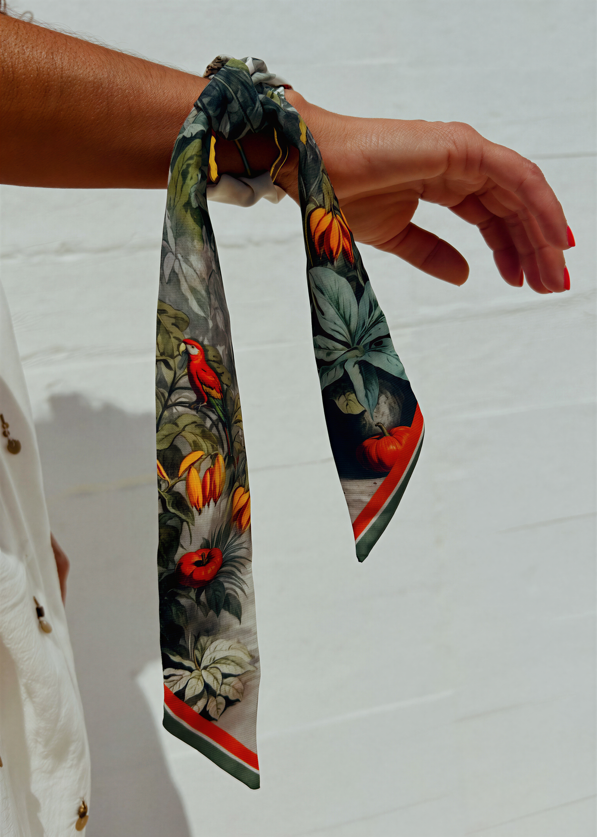 A colorful scarf is wrapped around a person's wrist, with a white wall in the background.