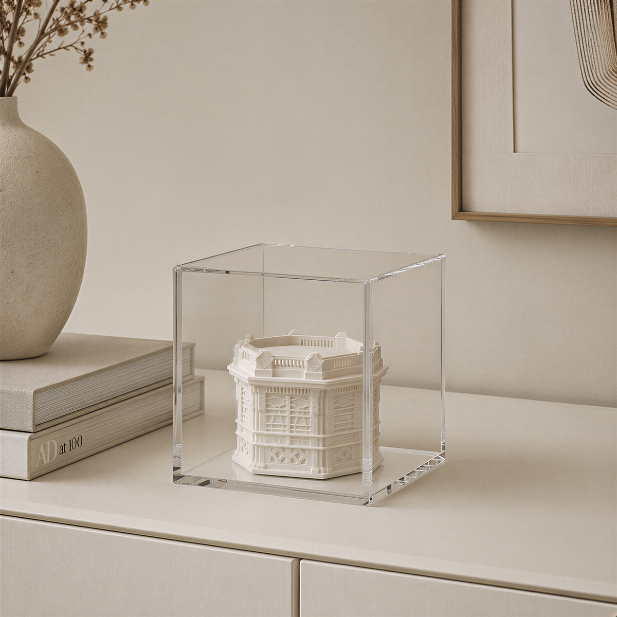 a clear glass display case containing a small white sculpture or model, placed on a white surface.
