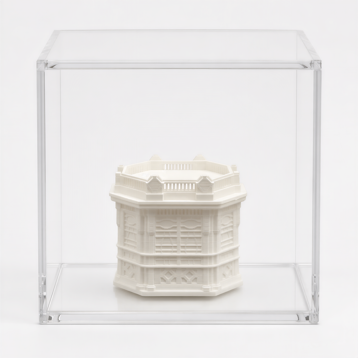 A white, three-dimensional sculpture is displayed in a clear glass case against a white background.